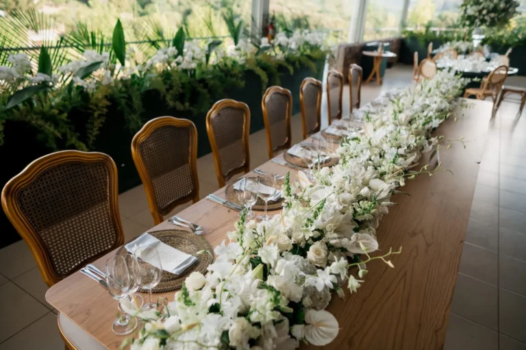 Long wedding table with white floral arrangement — 20-person wedding budget breakdown