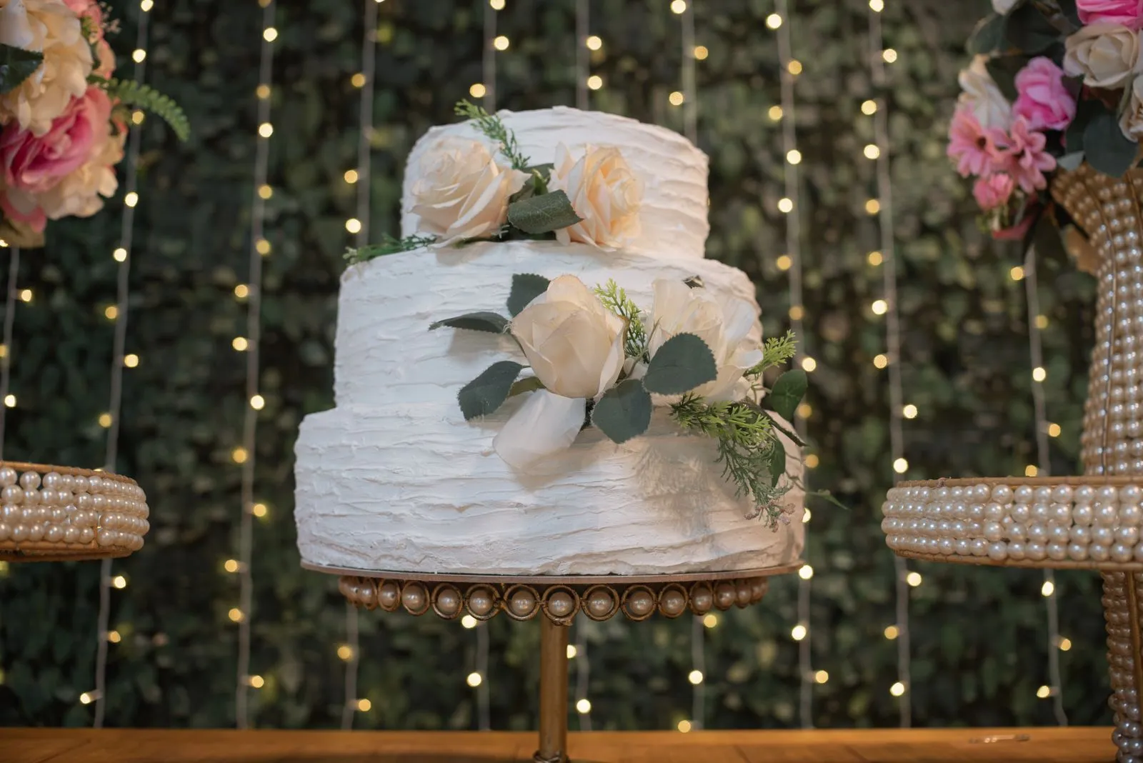 White two-tier wedding cake with flowers on a cake stand — 20-person wedding budget breakdown