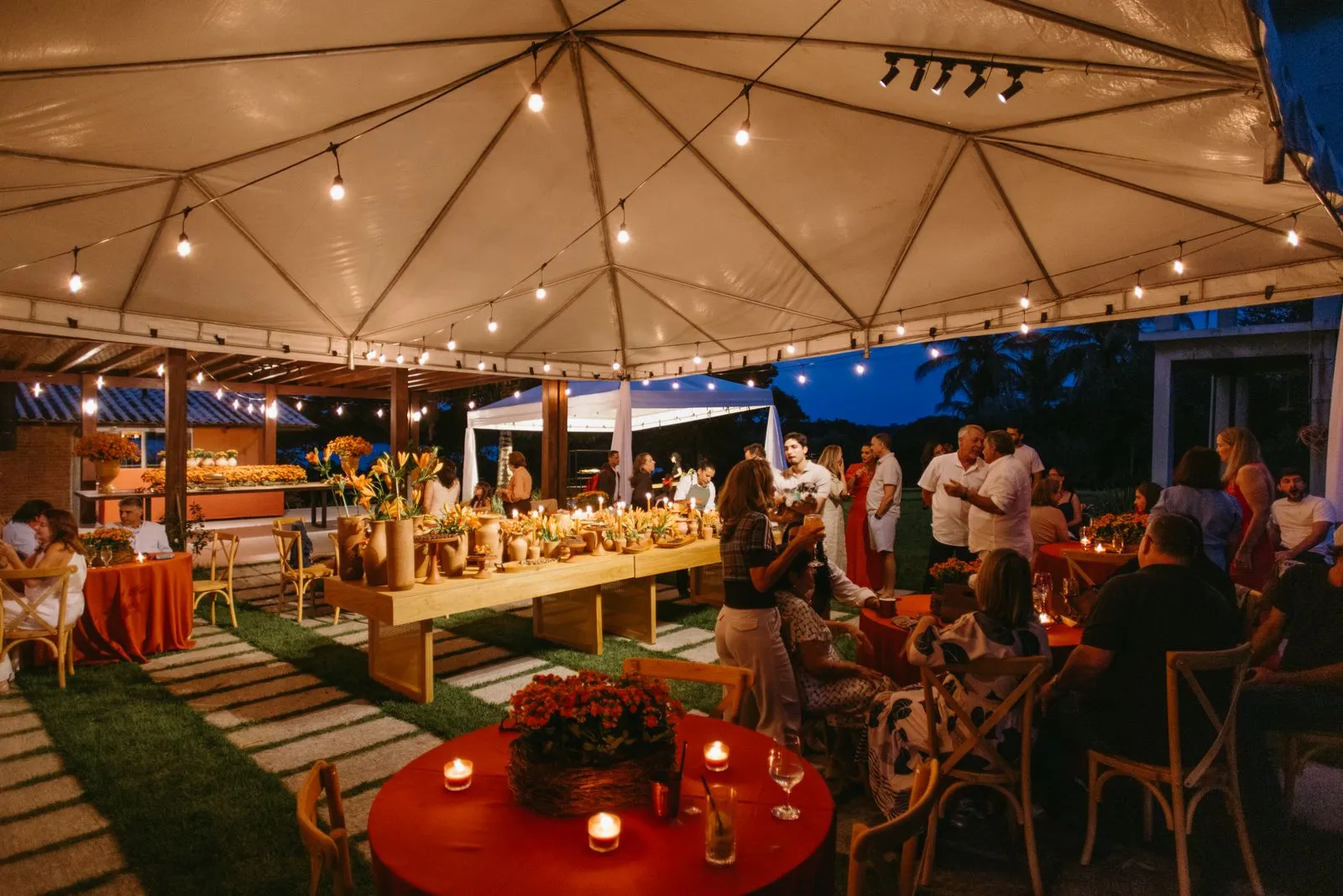 Evening outdoor wedding party under a tent with warm lighting — 50-person backyard wedding budget with food