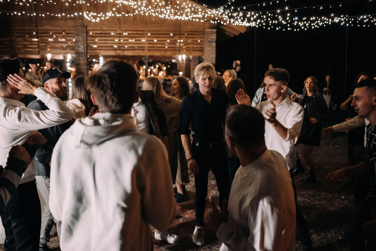 Guests dancing under string lights at a $5,000 budget wedding